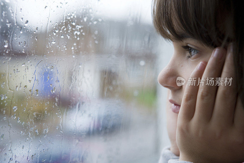 女孩望着窗外，雨水溅起的窗户