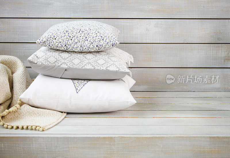 舒适的枕头和格子图案在浅色的木制背景上