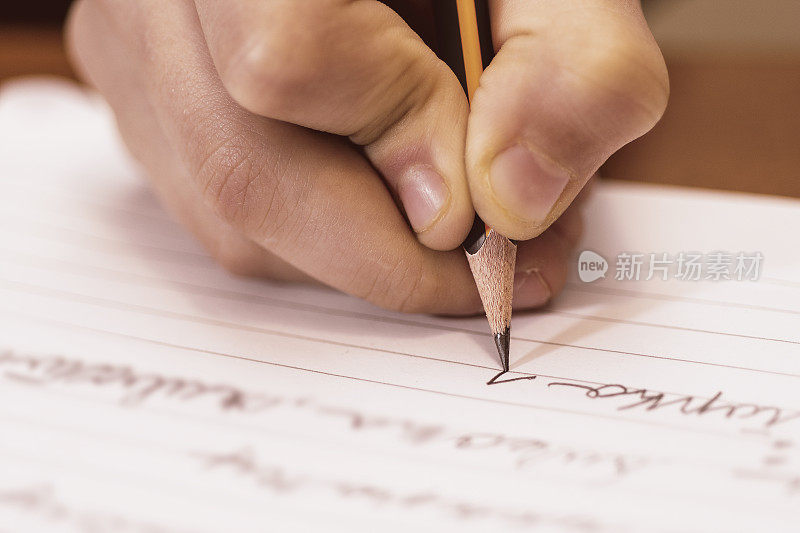 学校男孩写特写。铅笔在孩子的手里。