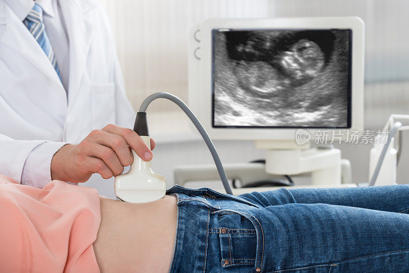 医生在孕妇腹部移动超声波探头