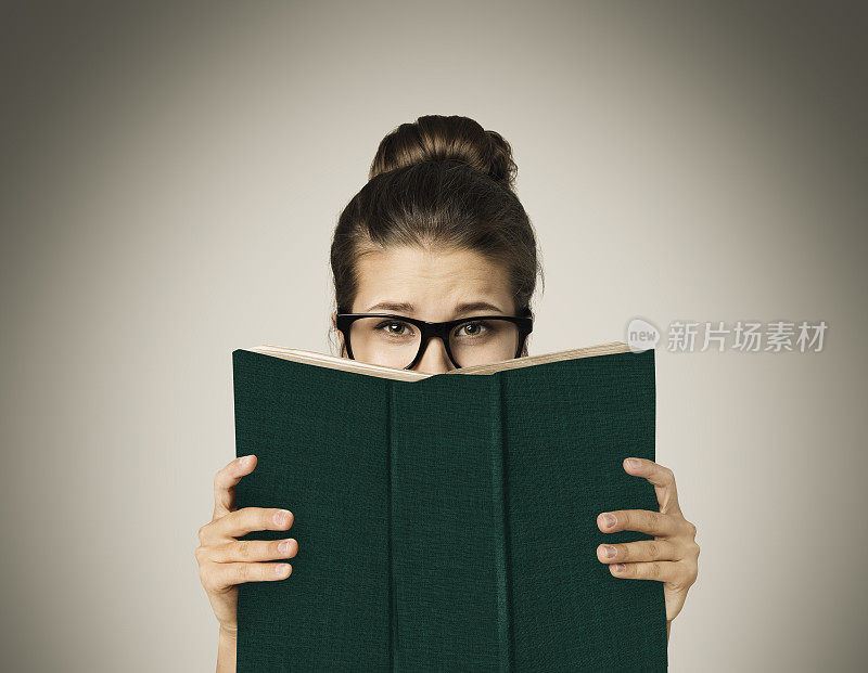 打开书隐藏的脸，女人的眼睛阅读在眼镜，灰色
