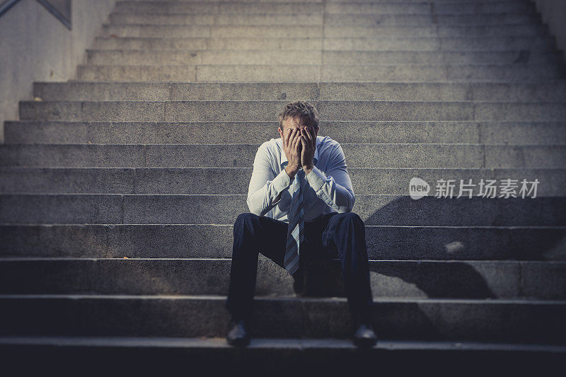 商人坐在街上的混凝土楼梯上，沮丧地哭泣