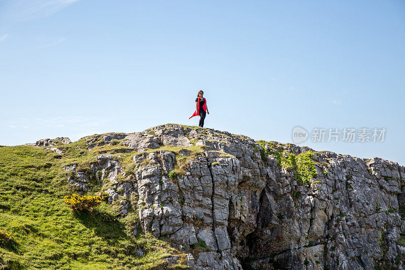 一个成熟的西班牙女人站在遥远的海岸岬角上