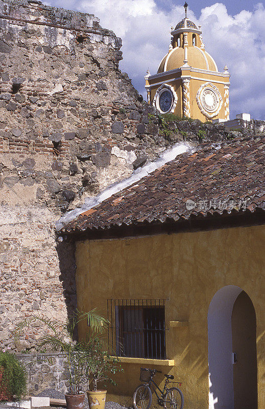 危地马拉安提瓜瓦片屋顶房屋上的老墙和教堂尖顶