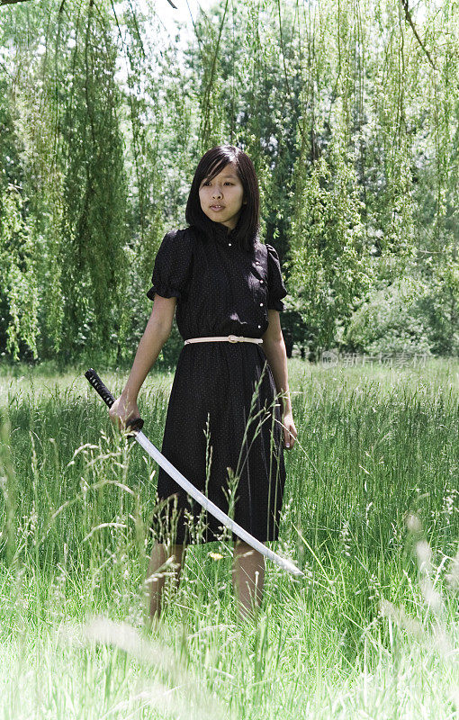年轻的忍者女孩在夏季连衣裙与武士刀