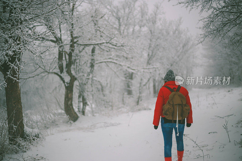 女徒步旅行者背包和雪鞋在雪地上的雪鞋