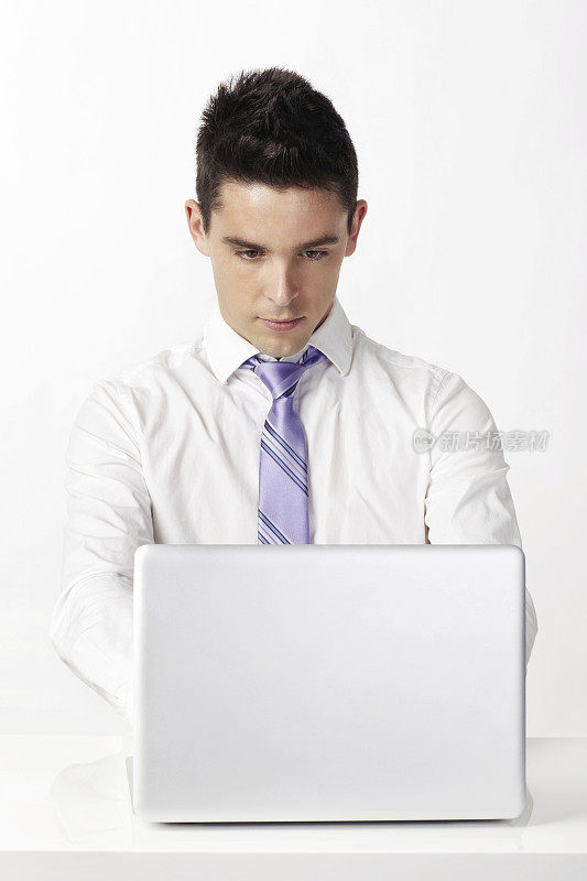 年轻的商人坐在笔记本电脑前工作