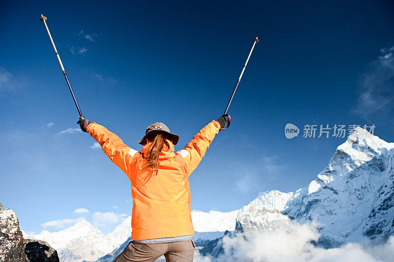 喜马拉雅山上一位女性登山者举起她的手臂表示胜利