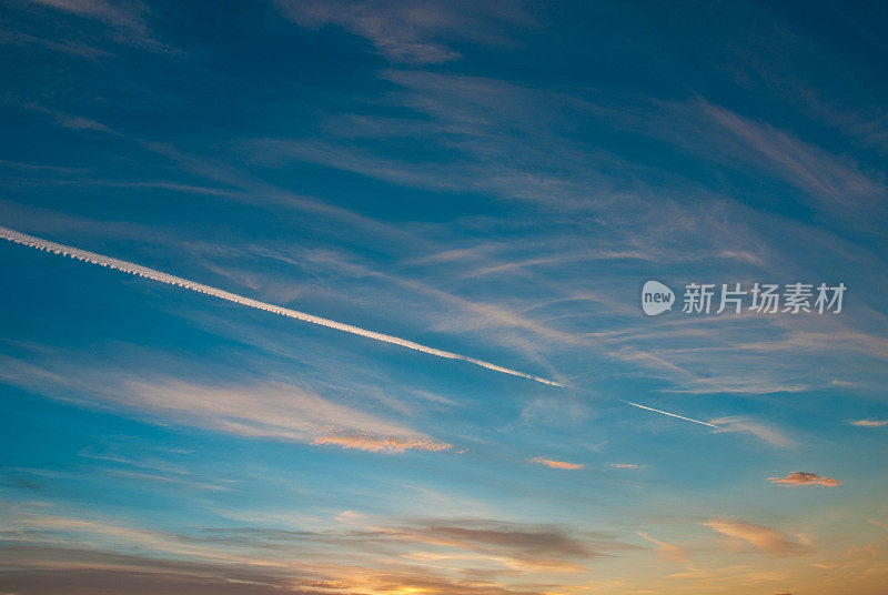 飞机与蒸汽条纹飞向美丽的夕阳