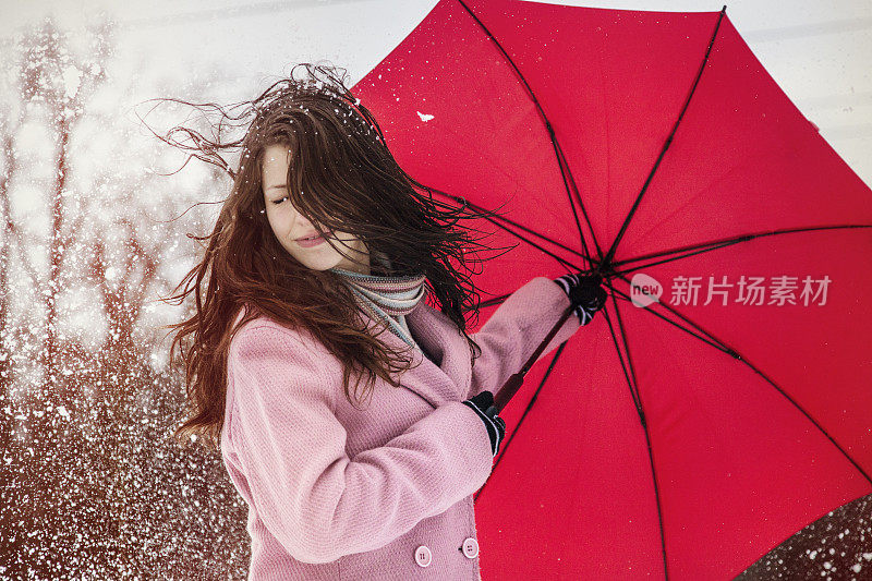 年轻的女性在暴风雪中撑着伞