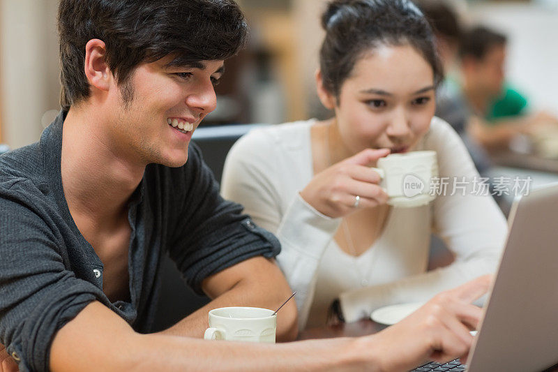 两个学生和他们的笔记本电脑在咖啡店