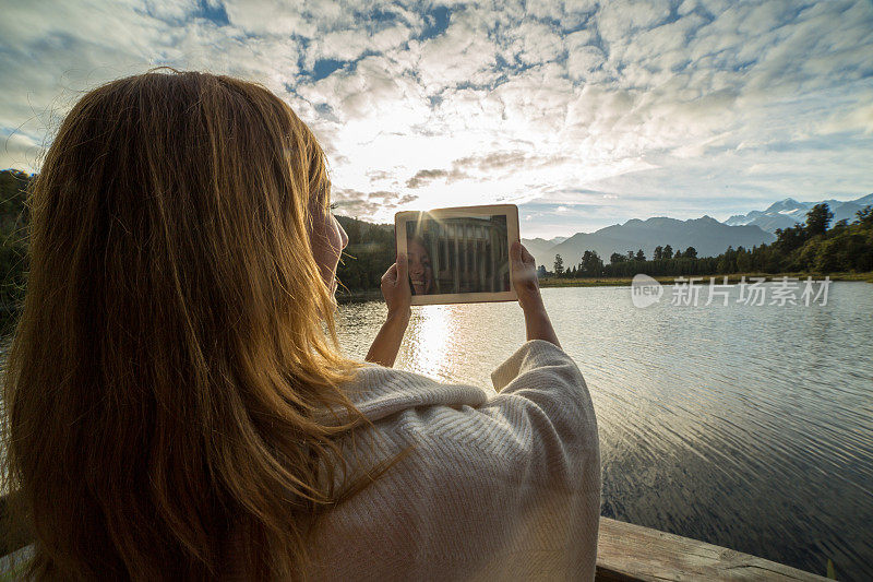 日出时分，女孩用平板电脑拍摄风景