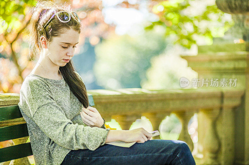 一个十几岁的女孩在秋天的公园里看书