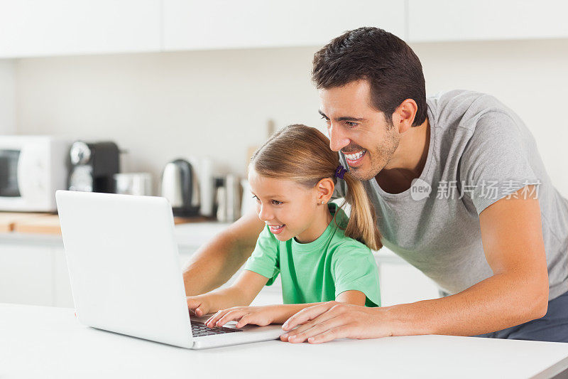 微笑的父亲和女儿使用笔记本电脑