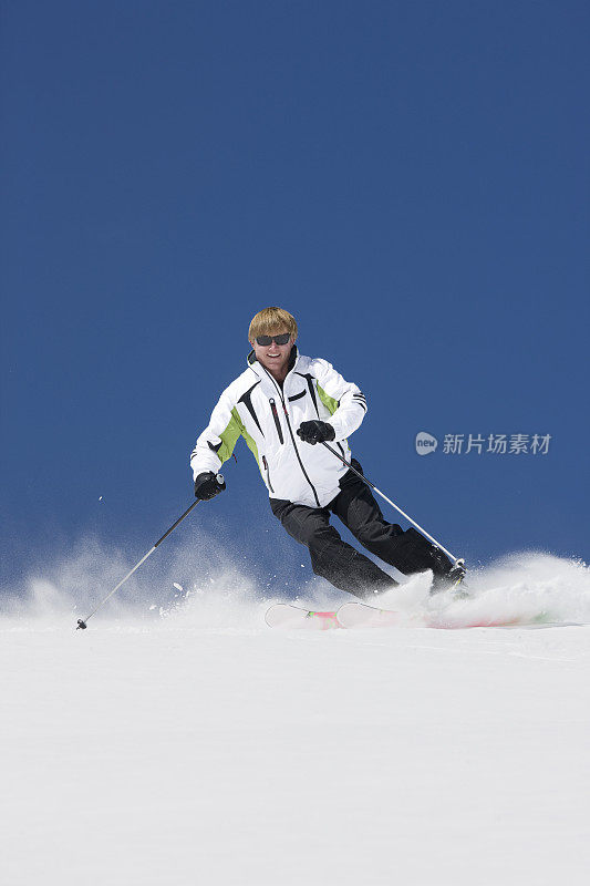 滑雪者迎着蓝天扫雪