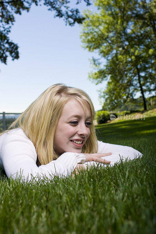 阳光灿烂的一天，金发少女躺在草地上，Copyspace