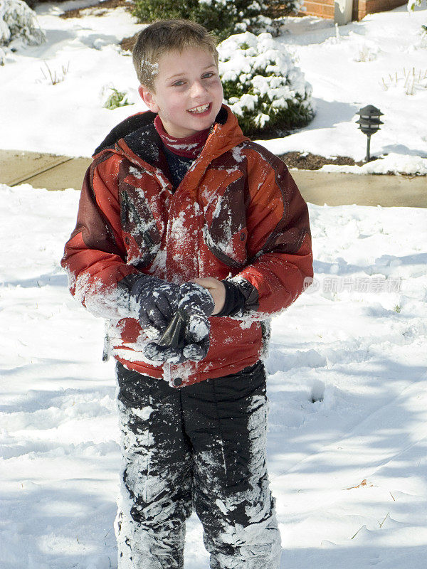 满脸笑容的白雪小男孩站在院子里