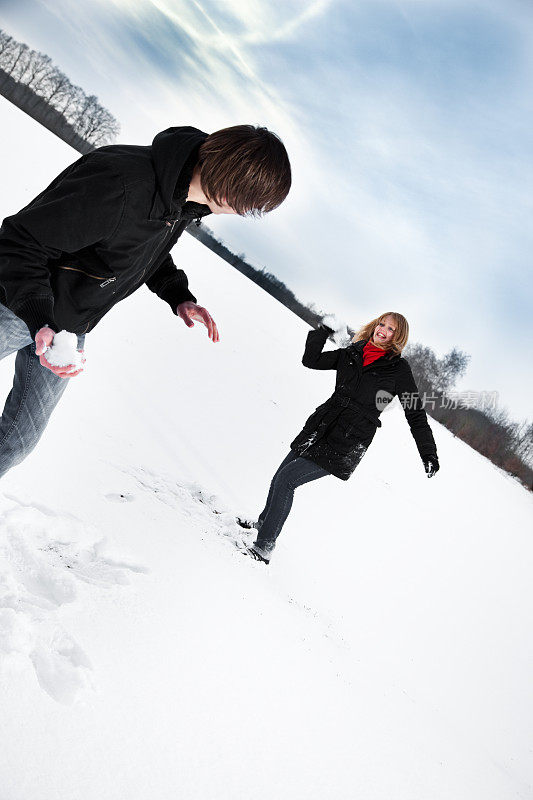 一对年轻夫妇在打雪仗，玩得很开心