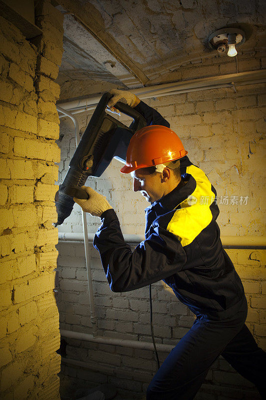 建筑工手持穿孔器和钻孔砖墙