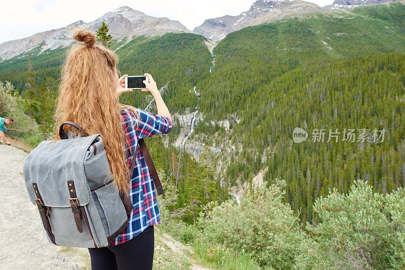 年轻漂亮的女背包客用手机拍照