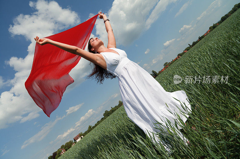 年轻女子手持红围巾在赛场上迎风而行