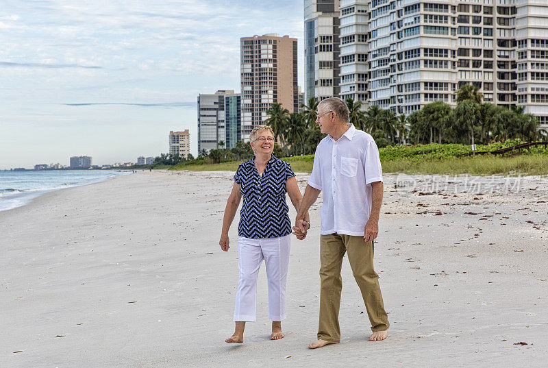 两位老人一边享受退休生活一边在海滩上散步