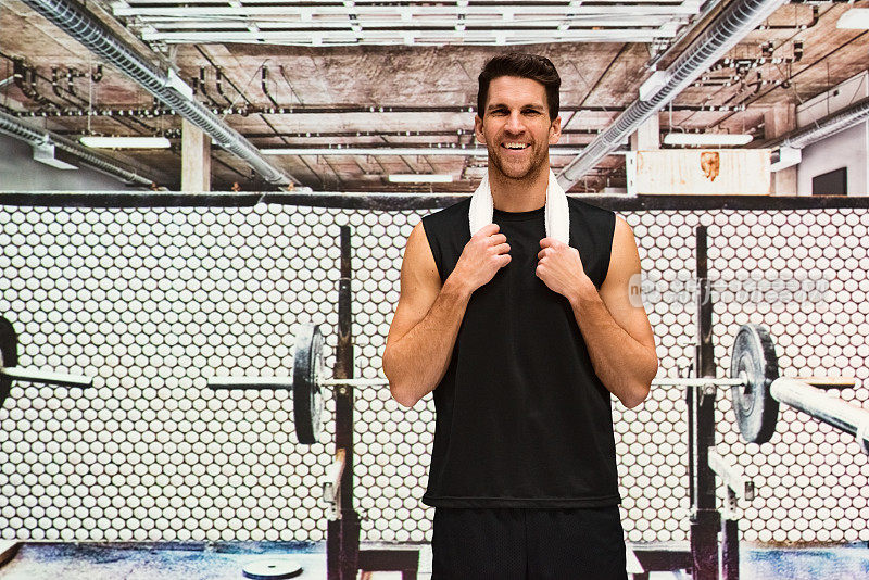 微笑的肌肉男站在健身房