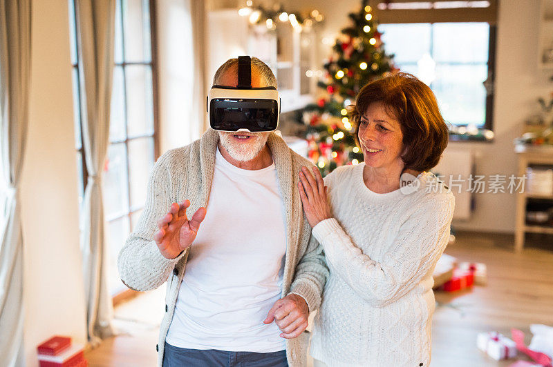 一对老年夫妇戴着VR眼镜站在圣诞树前。