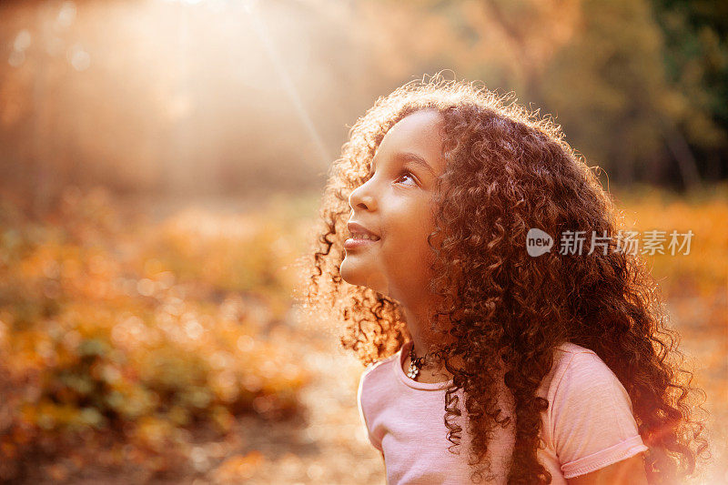 美国黑人可爱的卷发小女孩接受来自天空的神奇阳光