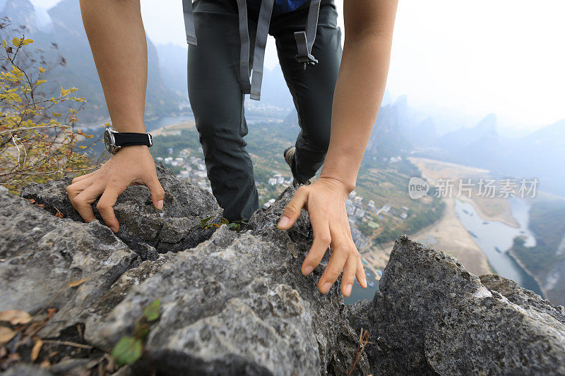 勇敢的女背包客攀登岩石在山顶悬崖边缘