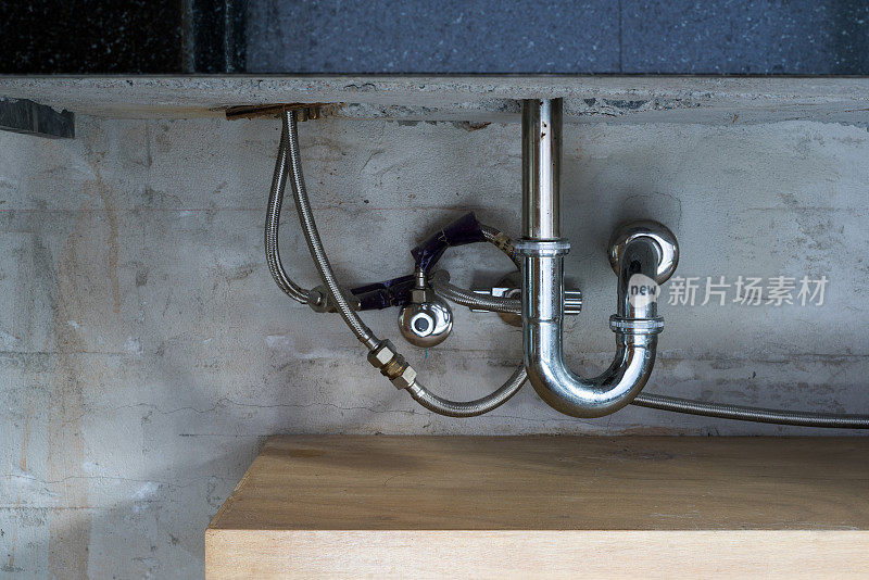浴室的钢制水槽管，陷阱和排水在混凝土墙上