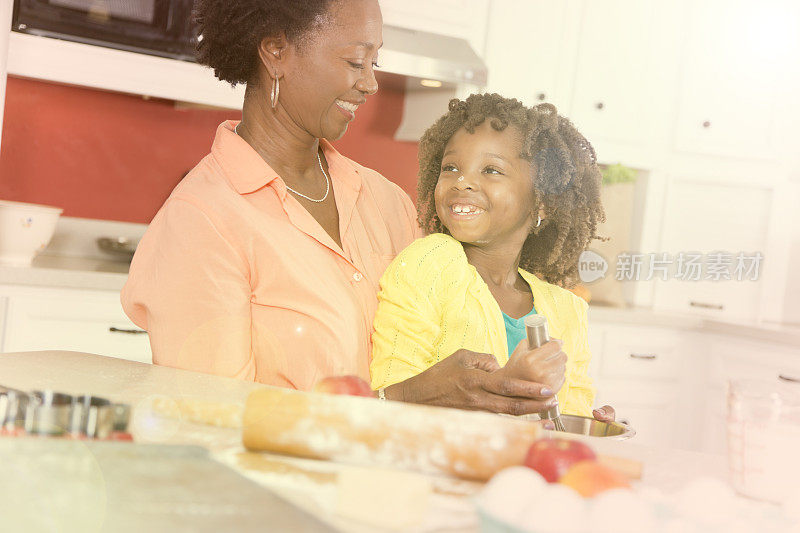祖母或母亲和女儿一起在家庭厨房烘焙。