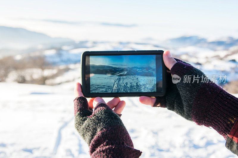 男人在冬天用智能手机拍照
