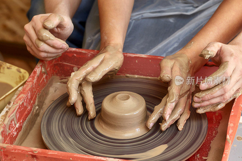 两个人的双手创造出锅，陶工的车轮。教学陶器