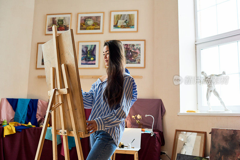 受启发的年轻女子在自己的艺术工作室画画