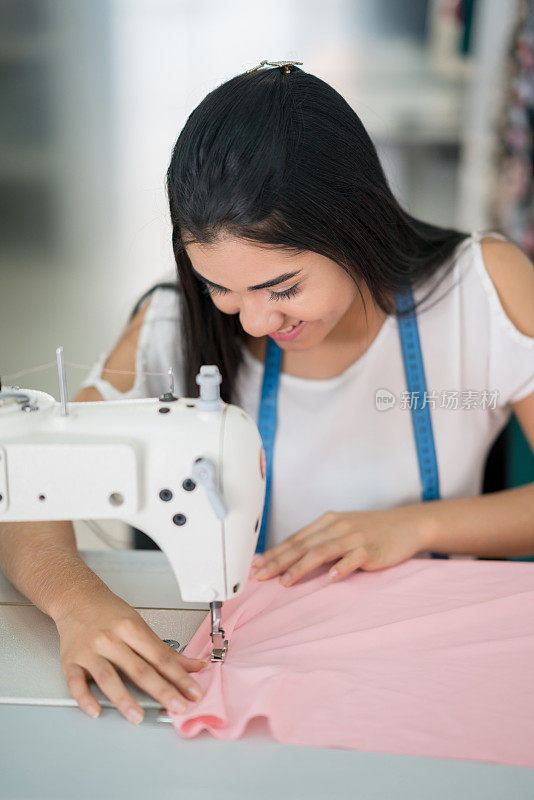 年轻的女裁缝在工作室里缝制