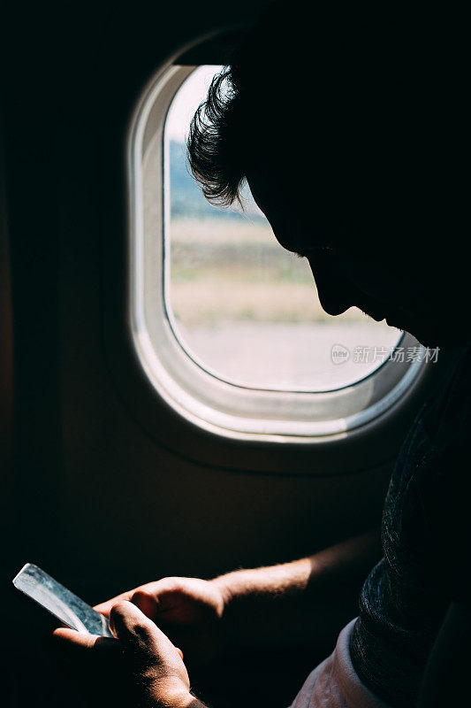 在飞机上使用手机的年轻人