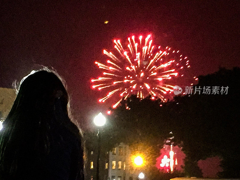 小女孩坐在爸爸的肩上，在倾盆大雨中看烟花