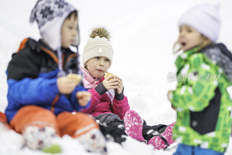 孩子们坐在雪地里吃零食