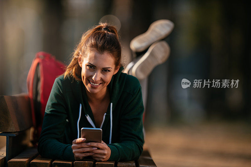 漂亮的年轻运动女性与智能手机在户外