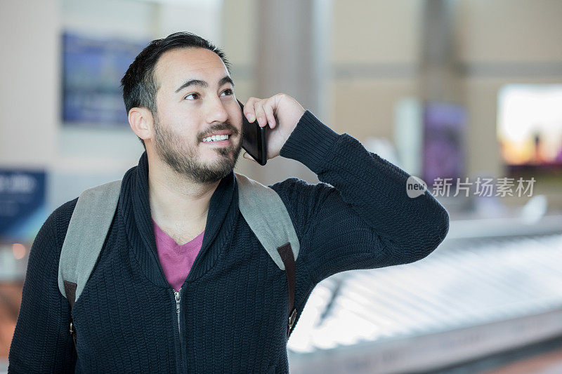 西班牙裔男子在机场行李提取区打电话