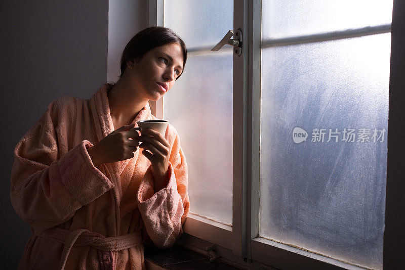 在窗前喝咖啡的女人