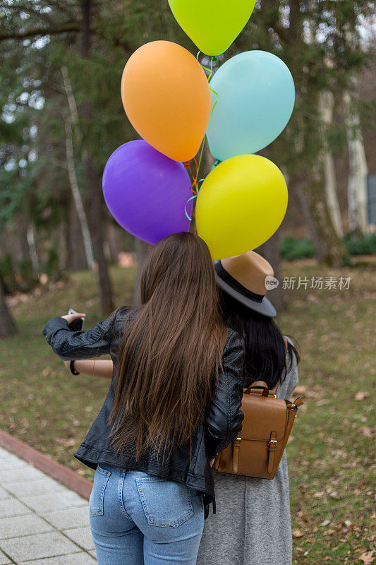 两个女性朋友拿着氦气球自拍