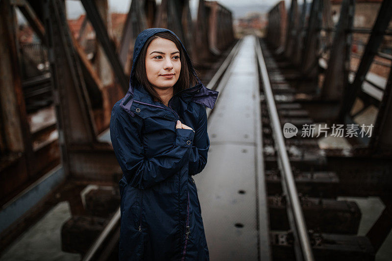 下雨天，年轻女子在铁路桥上