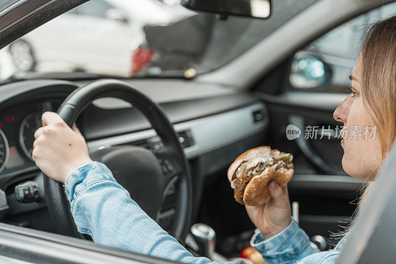 开车的时候拿着汉堡的女人