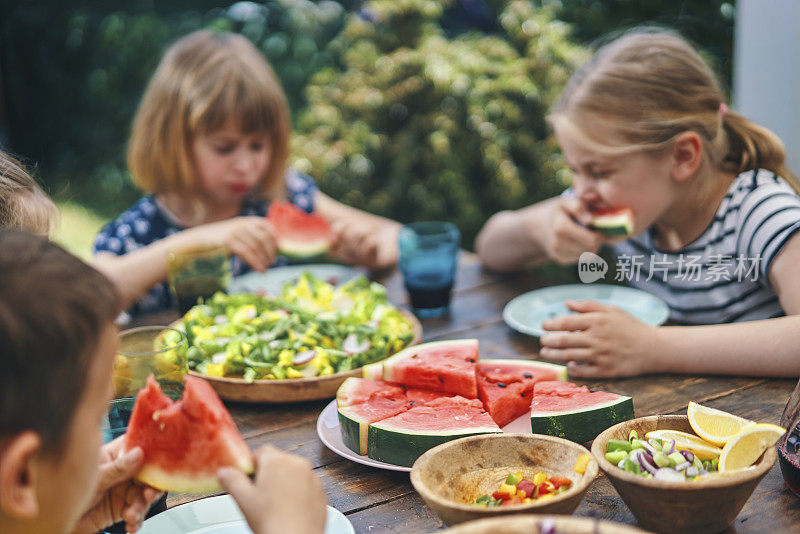 小孩子在外面的花园里吃新鲜的西瓜