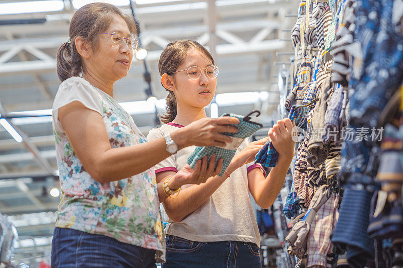 亚洲家庭母亲和十几岁的女孩喜欢在销售商店购物中心度假购物