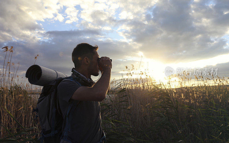 年轻的旅行者用双筒望远镜观察大自然。旅游度假概念