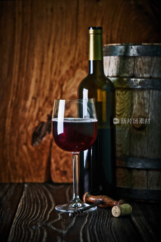 葡萄酒瓶，葡萄酒桶，葡萄酒杯与一个螺旋和软木塞射击在乡村纹理木制桌子。