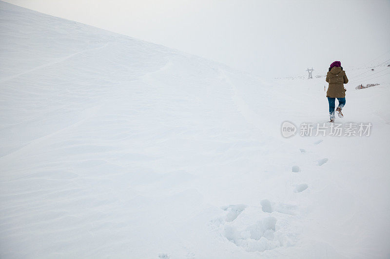 穿着暖和的衣服在雪地上行走的女人